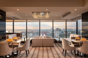 Enjoy a panoramic city view from the comfort of this stylish room, featuring a plush sofa set and dining area.