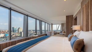 A modern hotel room with a large bed, a seating area, and a city view. - Yangon Thanlwin Hotel (Yangon)
