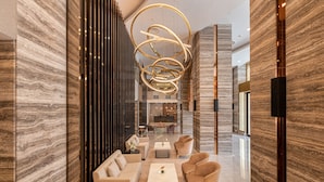A modern lobby with a marble wall, a central seating area with sofas and a coffee table, and a unique circular light fixture. - Yangon Thanlwin Hotel (Yangon)