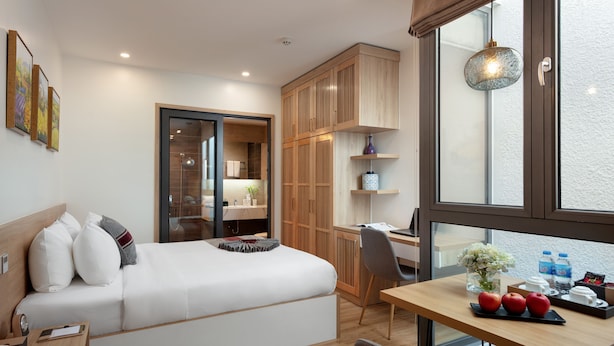 A modern hotel room with a bed, desk, and wardrobe.