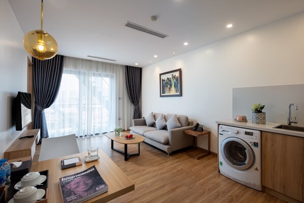 A modern living room with a sofa, coffee table, and a washing machine. - The Galaxy Home Hotel & Apartment (Hanoi)
