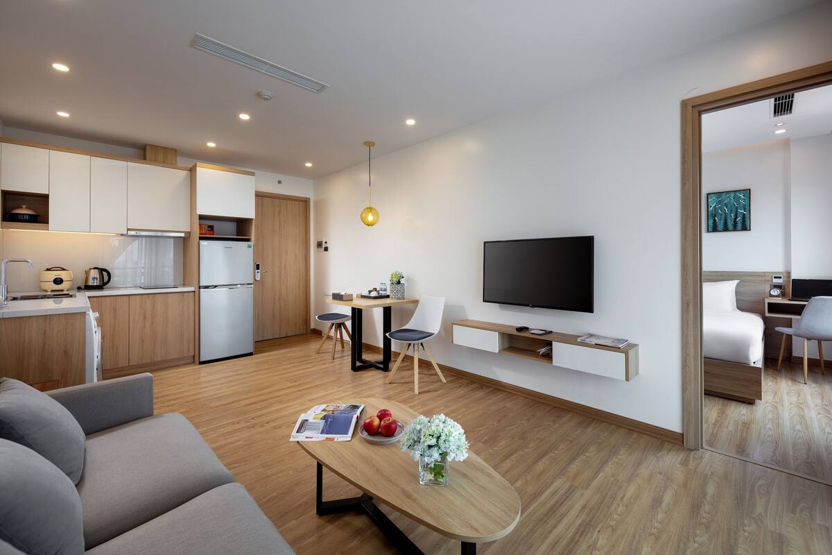 A modern living space with a kitchen, dining area, and a TV mounted on the wall.