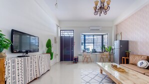 A modern living room with a flat-screen TV, a wooden coffee table, a sofa, and a patterned rug. - Sakura B&B (Taitung)