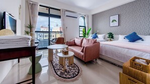 A modern hotel room with a sofa, a bed, a small table, and a balcony with a view. - Sakura B&B (Taitung)
