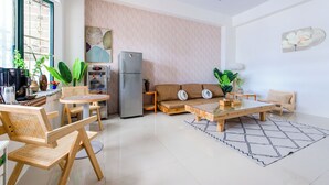 A modern living room with a sofa, chairs, a dining table, and a refrigerator. - Sakura B&B (Taitung)