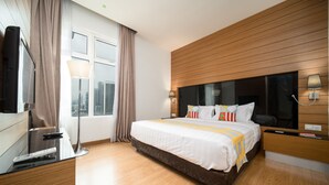 A modern hotel room with a large bed, wooden paneling on the walls, a flat-screen TV, and a desk with a lamp. - OYO Home 89311 Marvelous 1br Starview (Gelang Patah)