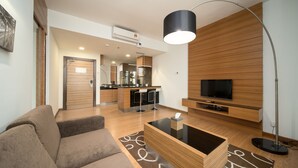 A modern living room with a sofa, coffee table, TV, and a kitchen area in the background. - OYO Home 89311 Marvelous 1br Starview (Gelang Patah)