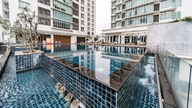 A modern hotel with a central swimming pool surrounded by high-rise buildings. - OYO Home 89311 Marvelous 1br Starview (Gelang Patah)