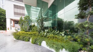 A modern building with large glass windows and a landscaped area with various plants and a small tree. - OYO Home 89311 Marvelous 1br Starview (Gelang Patah)
