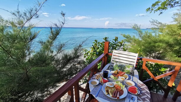 Ein Tisch reichhaltig mit Frühstücksleckereien gedeckt mit Blick auf einen Strand.