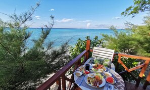 Ein Tisch reichhaltig mit Frühstücksleckereien gedeckt mit Blick auf einen Strand.