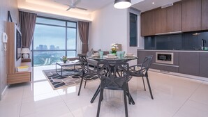 Une cuisine moderne avec des meubles en bois foncé, un four encastré et un coin repas comprenant une table et des chaises en verre.