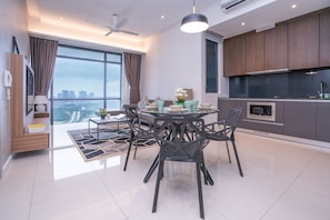 Enjoy a spacious dining area with a round table and contemporary chairs, a sleek kitchen with dark cabinets and stainless steel appliances, and a large window offering a panoramic city view.