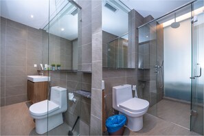 A modern bathroom with a glass shower enclosure, a toilet, and a sink.