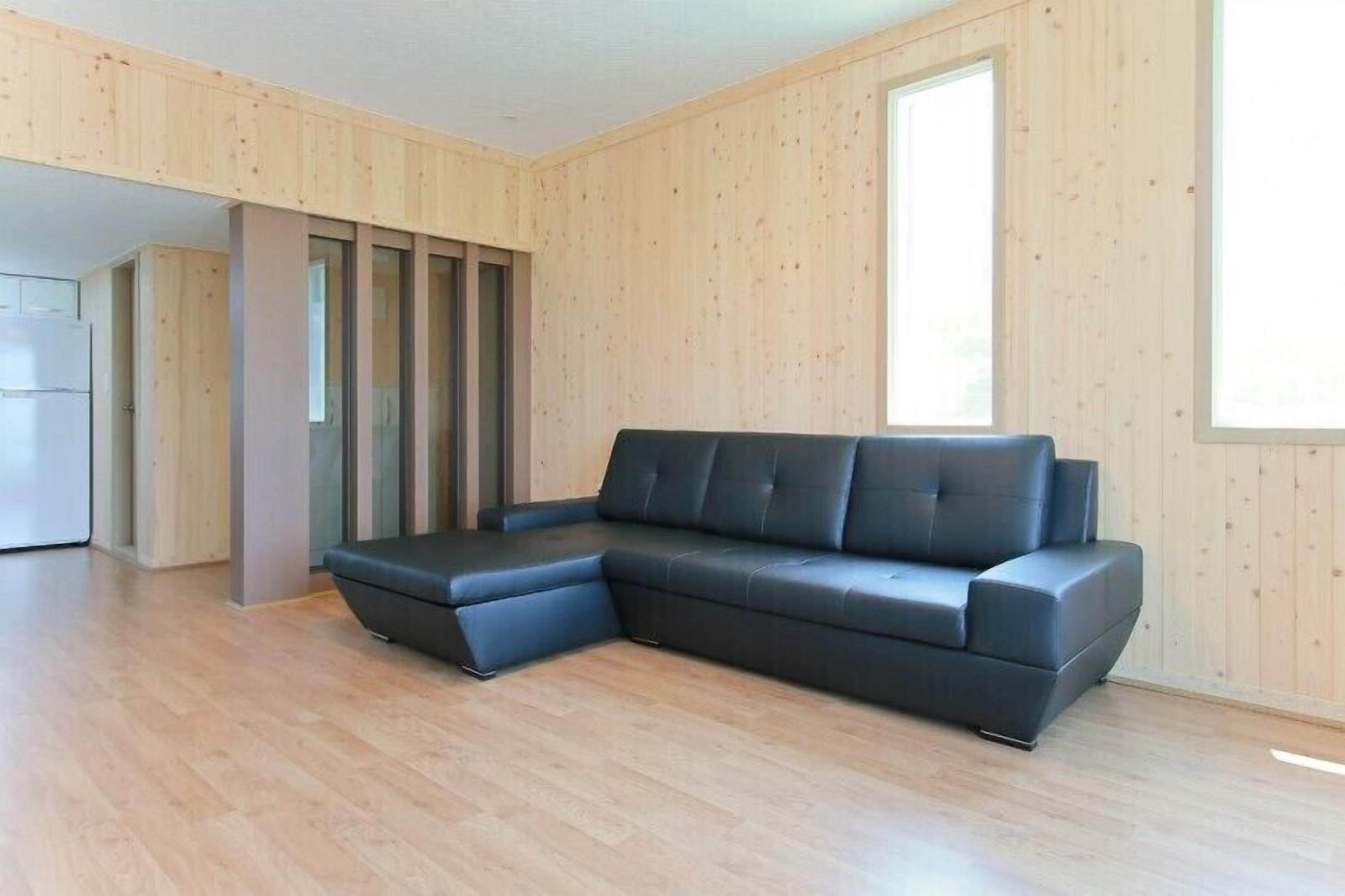 Un soggiorno moderno con un divano componibile, pareti in legno e una grande finestra.
