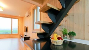 Una cocina moderna con escalera negra, paredes de madera y un amplio ventanal con vistas al exterior.