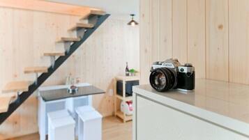 A modern interior with a wooden staircase, a dining area, and a camera on a counter.