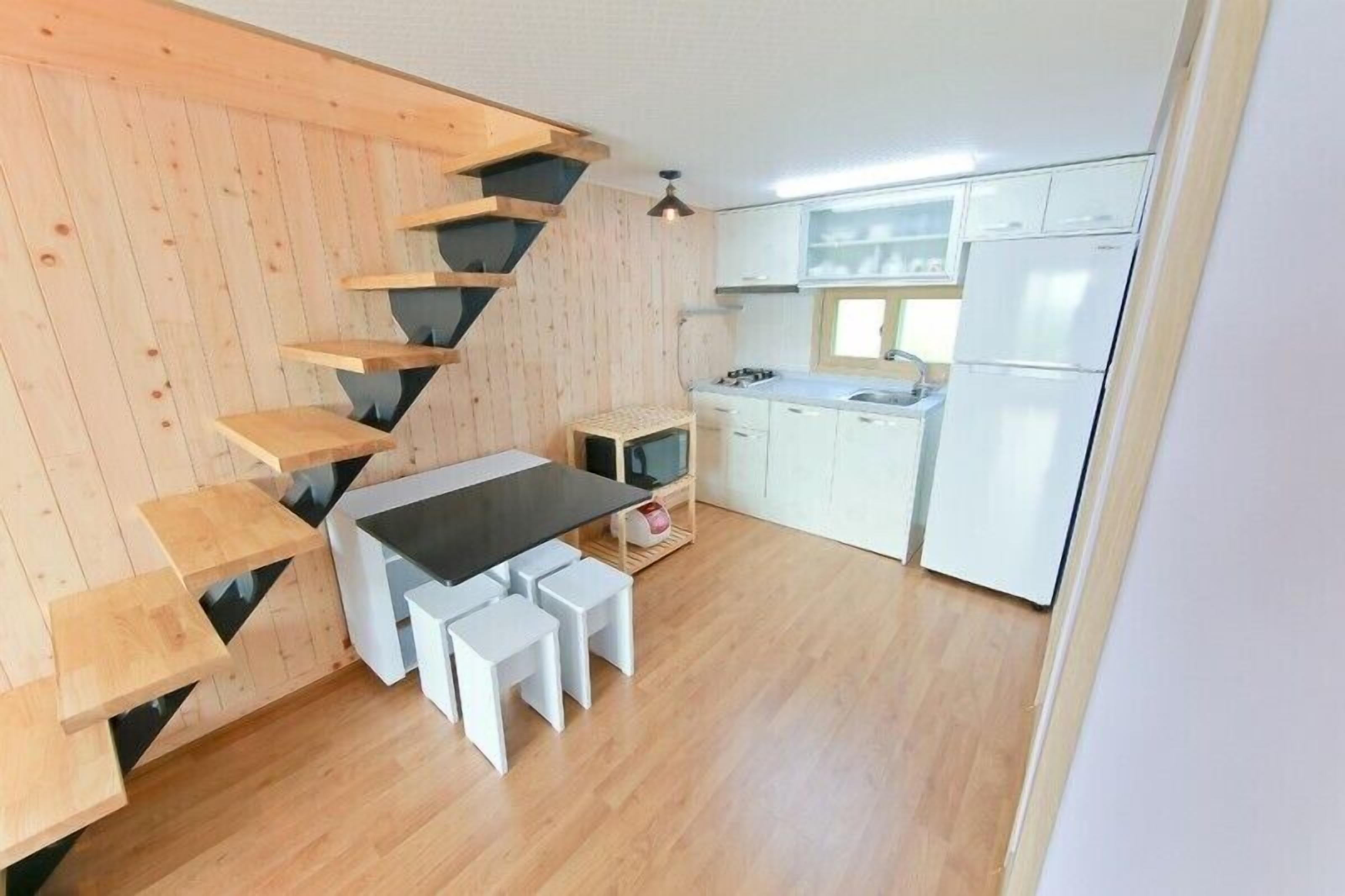 Una cocina con escalera de madera, armarios blancos y encimera negra.