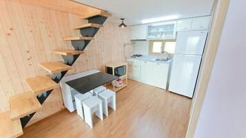 Una cocina con escalera de madera, armarios blancos y encimera negra.