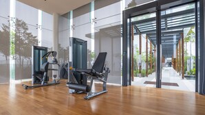 A modern gym with exercise equipment, large windows, and a view of a covered outdoor area. - OYO Home 89725 Beautiful 3br Grand Medini (Iskandar Puteri)