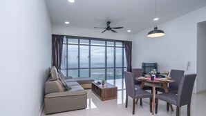 A modern living room with a sofa, dining table, chairs, and a ceiling fan. - OYO Home 89725 Beautiful 3br Grand Medini (Iskandar Puteri)