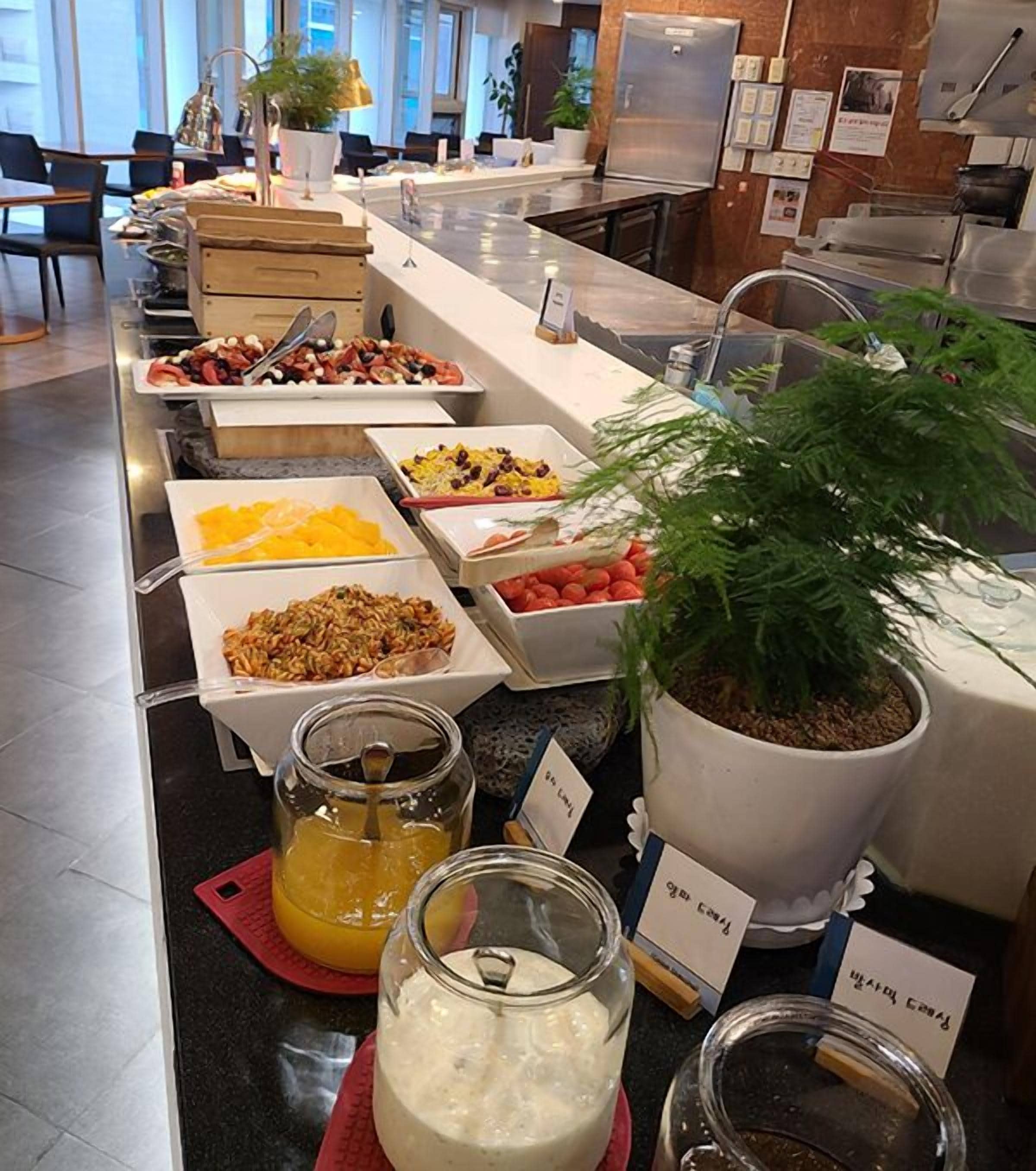 A buffet with various food items and beverages, including fruits, salads, and dairy products.