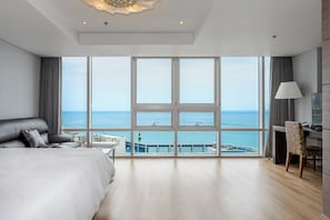 A modern hotel room with a large balcony, a bed, a desk, and a chair. - Haeundae Seacloud Hotel Residence (Busan)
