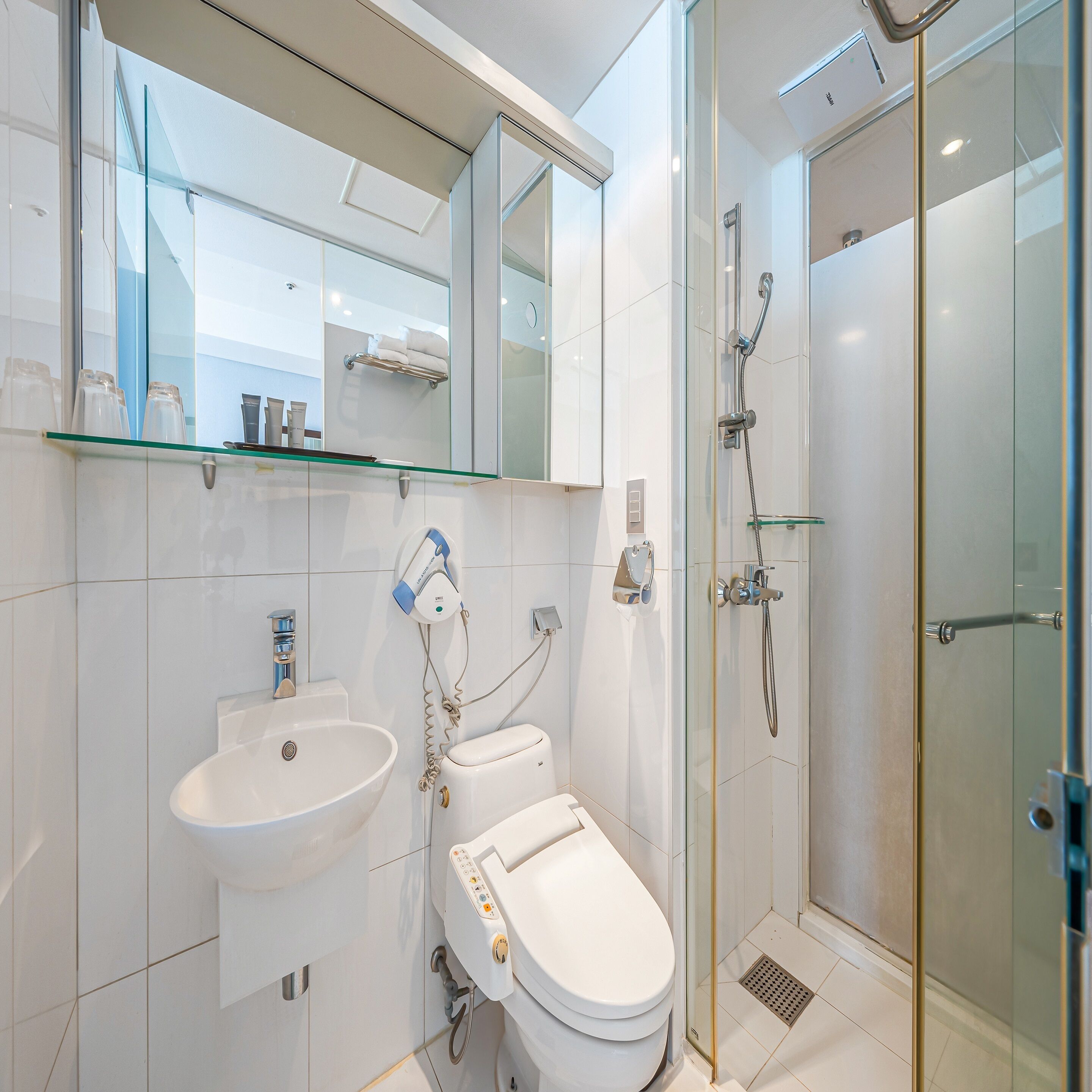 A modern bathroom with a glass shower enclosure, a white sink, and a toilet.