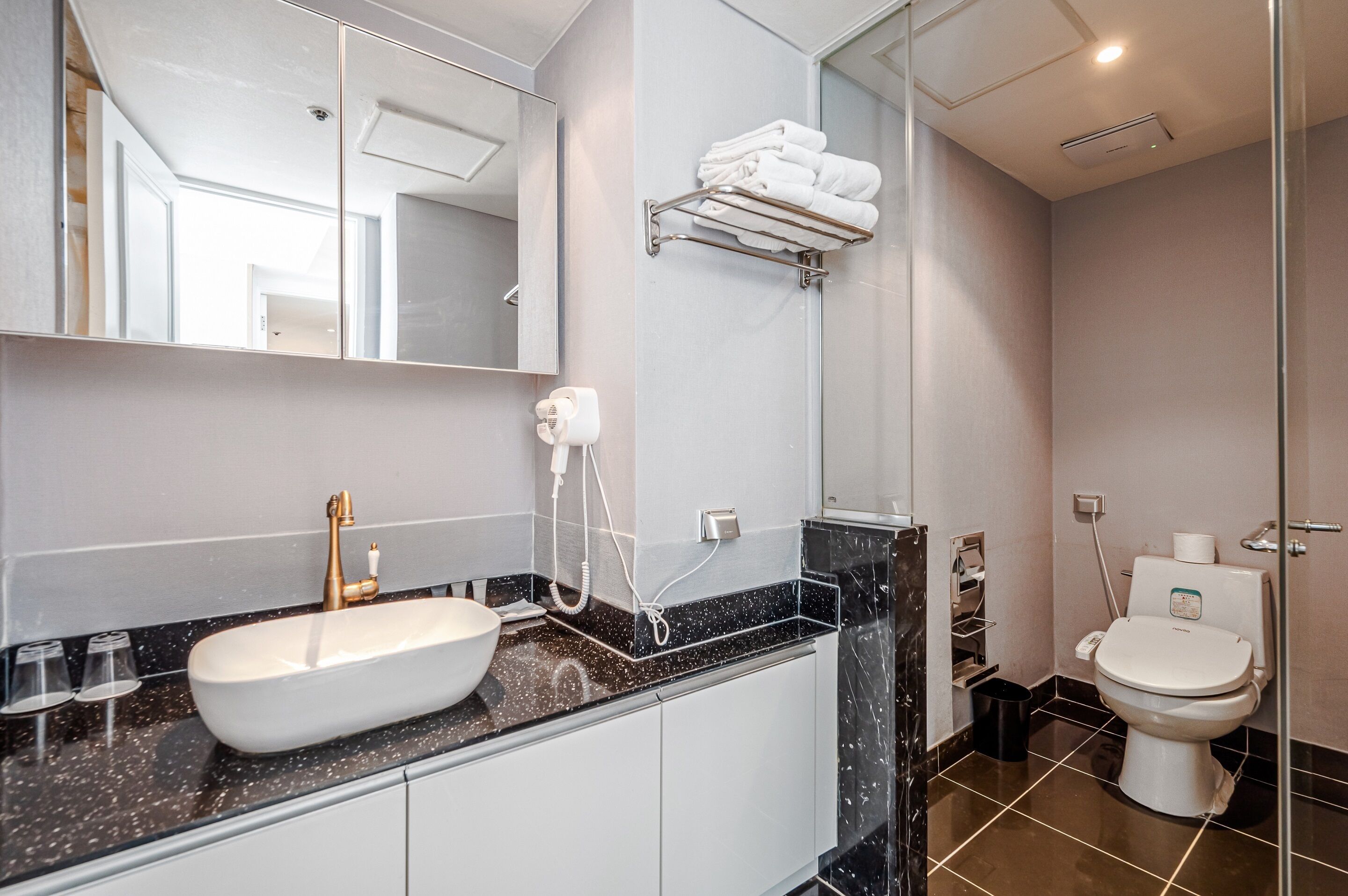 Un baño moderno con un lavamanos blanco, una cabina de ducha de vidrio y un inodoro.