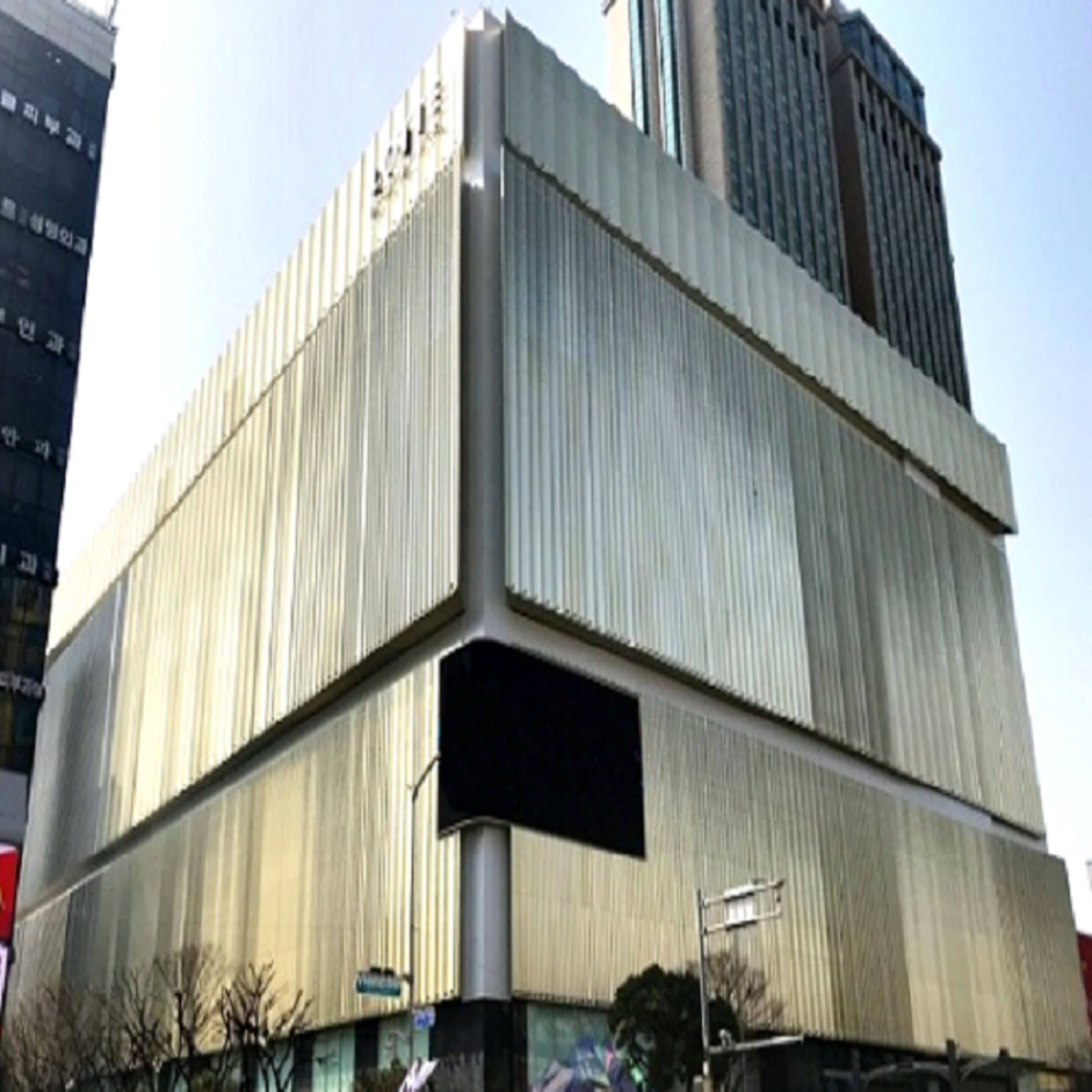 A large, modern building with a unique angular design, featuring a prominent entrance and a large open space at the base.