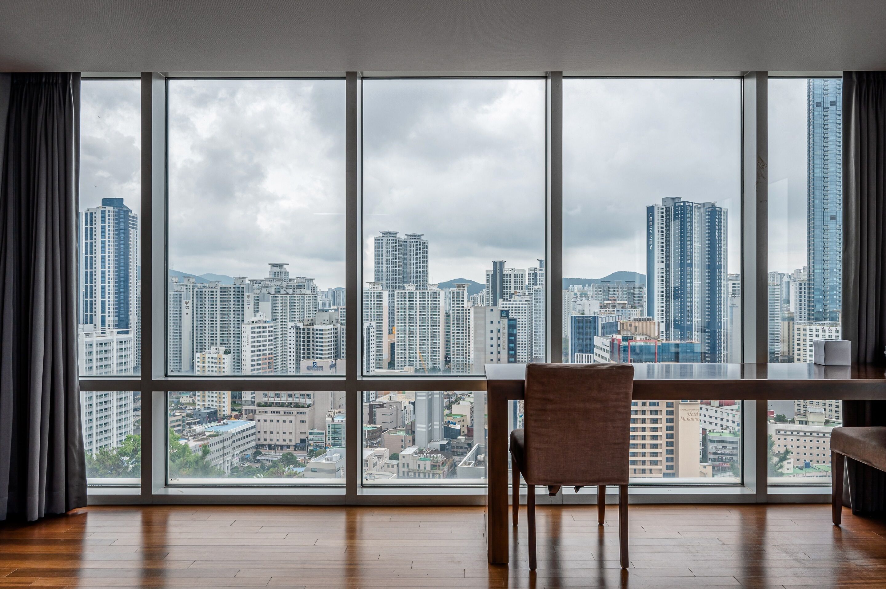 A room with a large window offering a city view.
