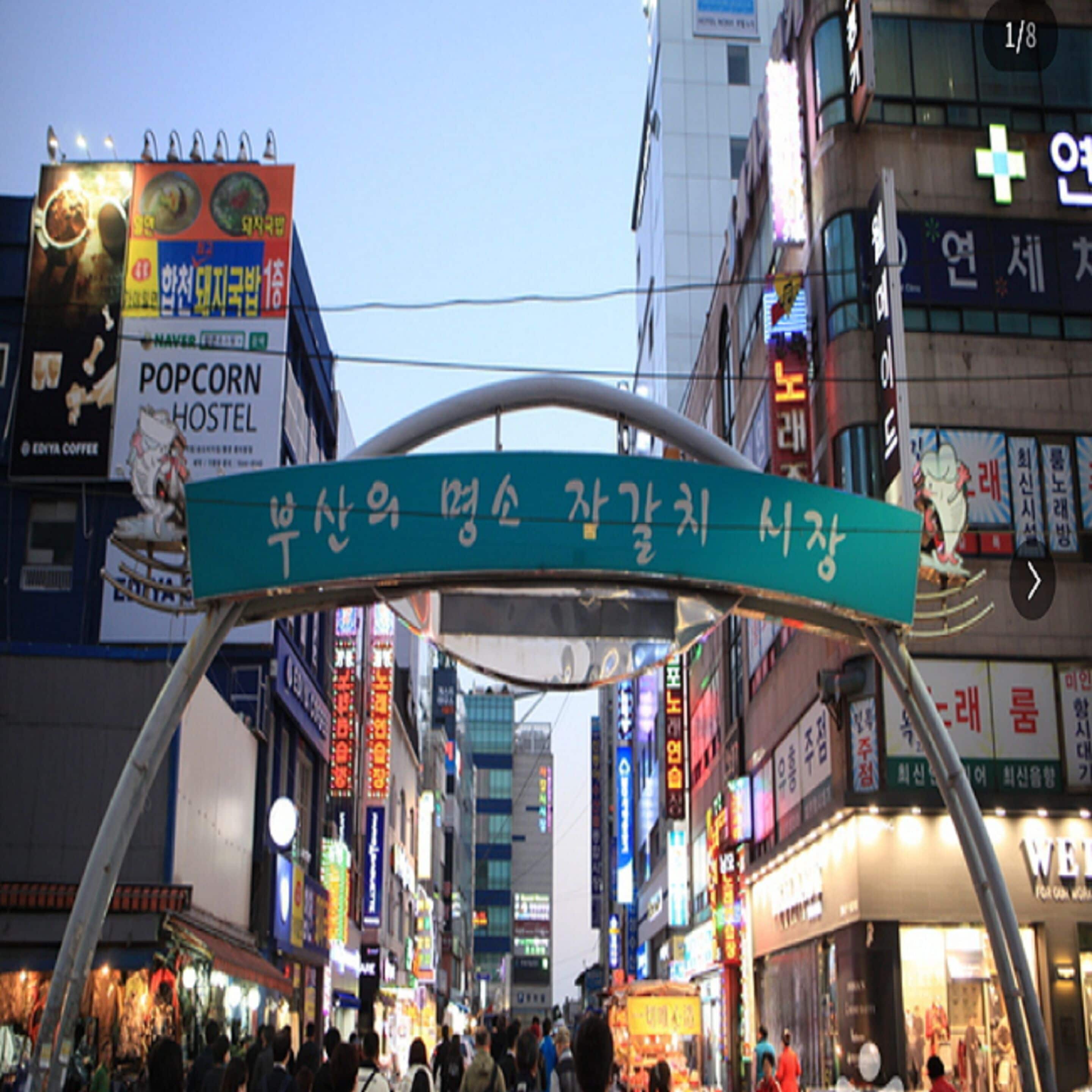 A busy urban street with various shops and signs, including a sign for a hostel.