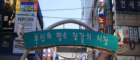 A busy urban street with various shops and signs, including a sign for a hostel.