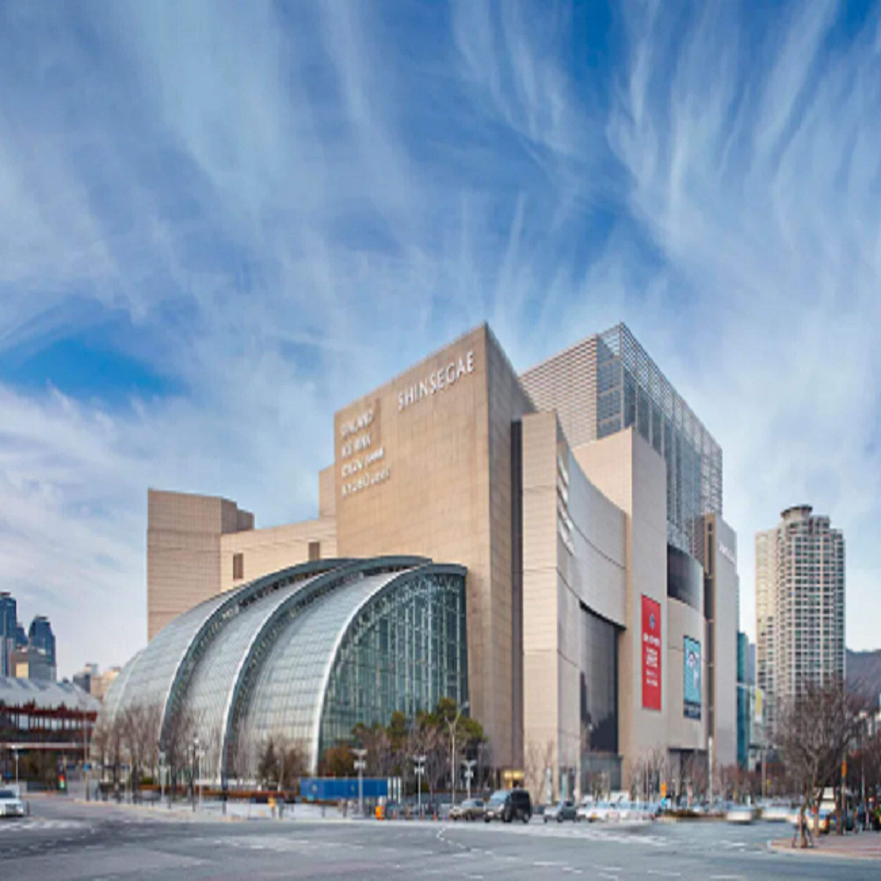 A modern building with a curved glass facade and a sign reading "SHINSEGAE."