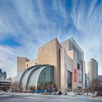 A modern building with a curved glass facade and a sign reading "SHINSEGAE."