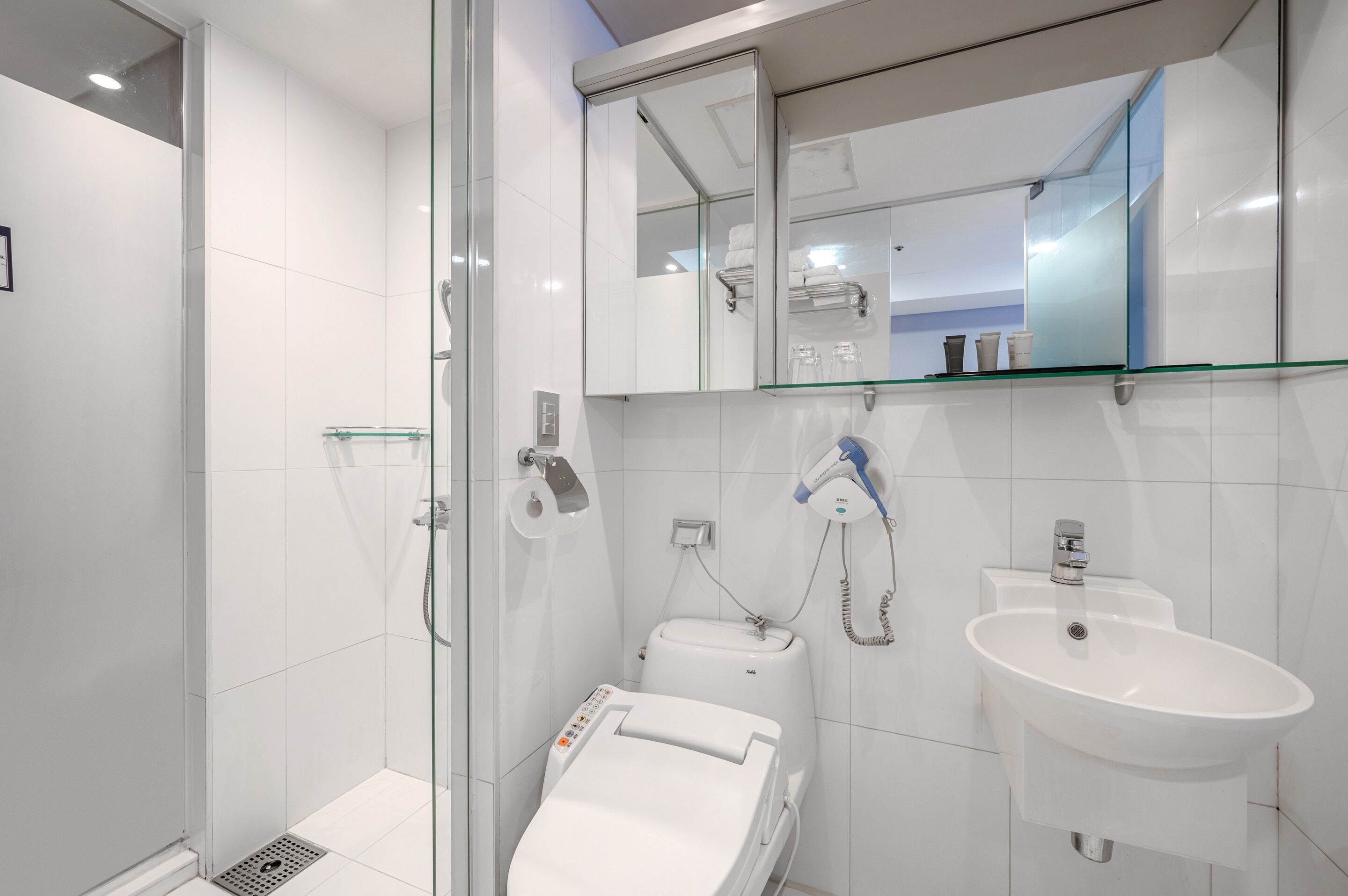 Un baño moderno con cabina de ducha de vidrio, inodoro y lavabo con espejo.