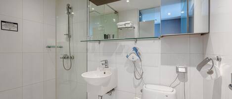 A modern bathroom with a glass shower enclosure, a white sink, and a toilet.