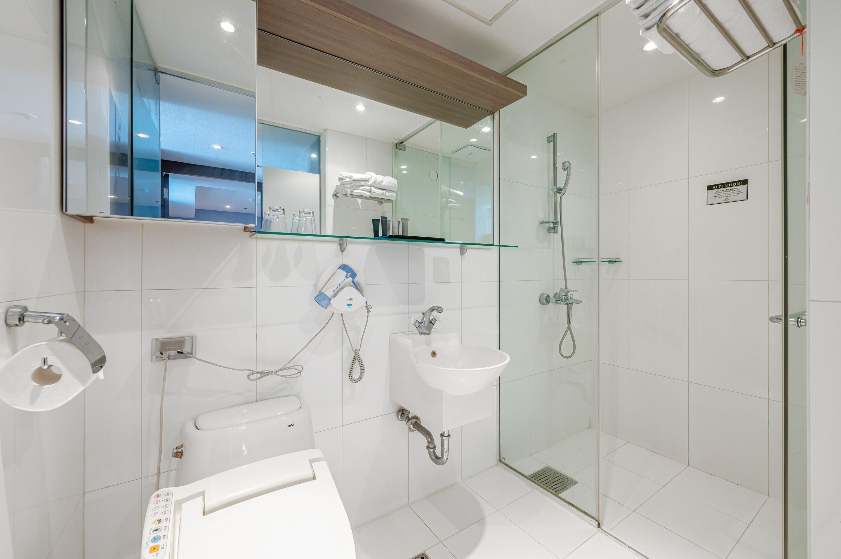 A modern bathroom with a glass shower enclosure, a white sink, and a toilet.