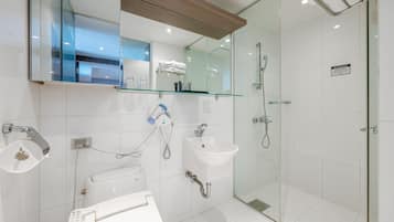 Uma casa de banho moderna com chuveiro em cabine de vidro, lavatório branco e sanita.