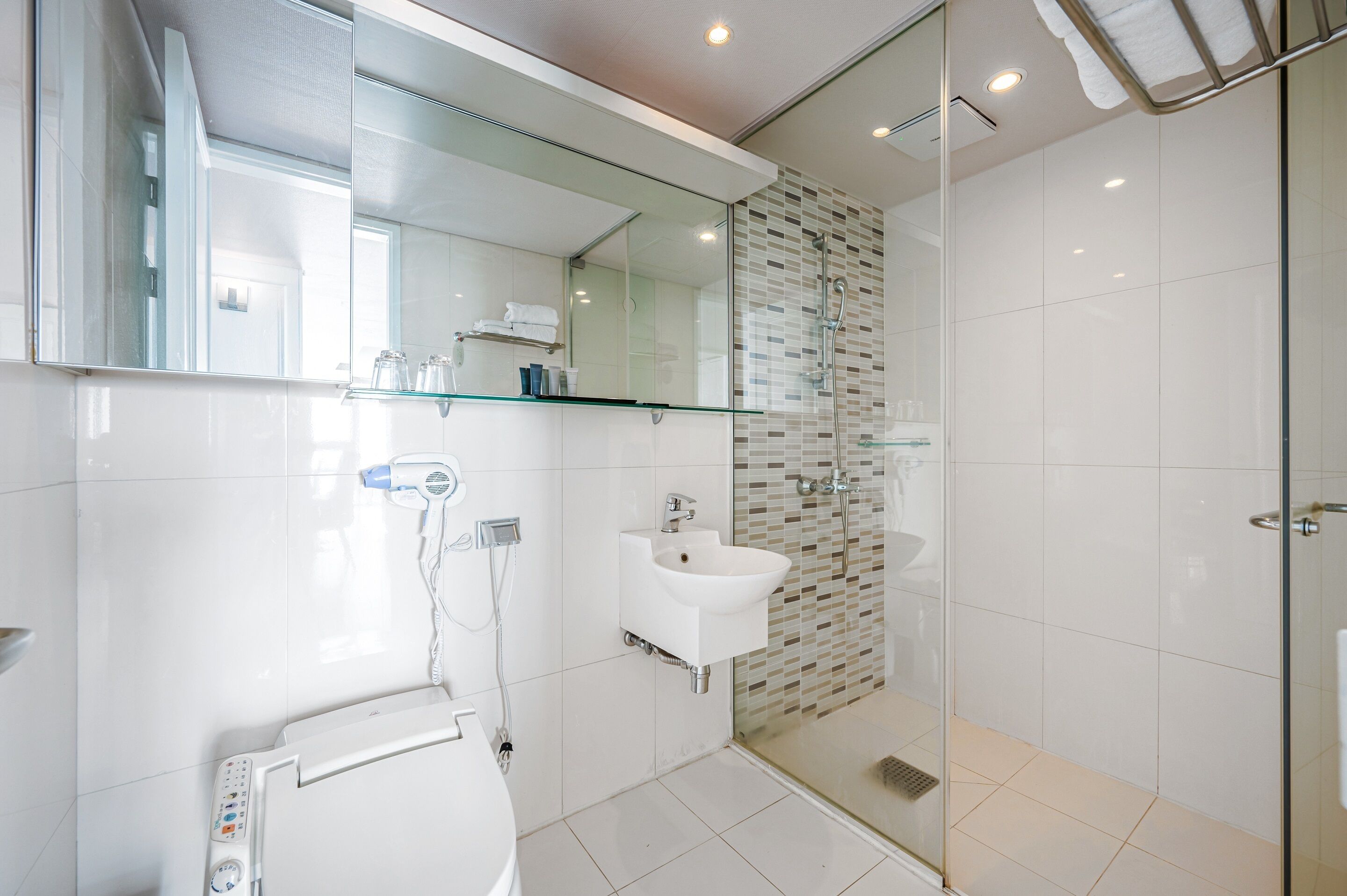 Ein modernes Badezimmer mit Duschkabine aus Glas, einem weißen Waschbecken und einer Toilette.