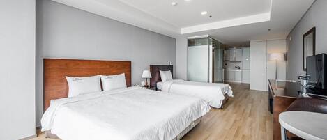 Una habitación de hotel con dos camas, un escritorio, una silla y un televisor.