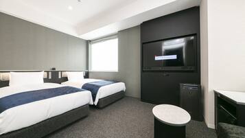 Habitación de hotel con dos camas, televisión, escritorio y una mesita.