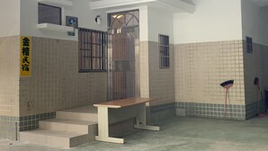 Une salle de bain propre, carrelée, avec un banc, des toilettes et un espace douche.