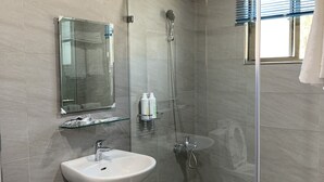Une salle de bain moderne avec une douche à parois de verre, un lavabo et un miroir.