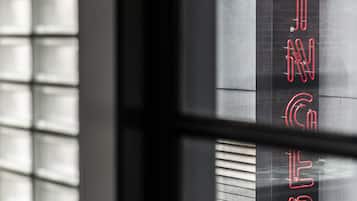 A window with blinds and a neon sign spelling "GINGERBIRD" in red.