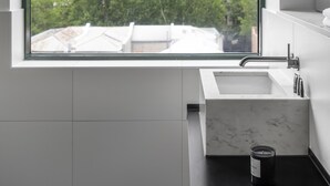 A modern bathroom with a large window, a sink, and a marble countertop. - Lancemore Crossley St Melbourne (Melbourne)