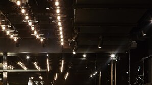 A modern restaurant interior with tiered seating, hanging pendant lights, and a bar area with stools. - Lancemore Crossley St Melbourne (Melbourne)
