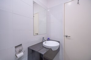 Ein Badezimmer mit Waschbecken, Spiegel und Toilettenpapierhalter.