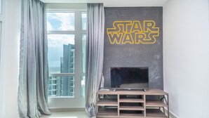 A modern living room with a Star Wars themed wall, a large window with curtains, and a flat-screen TV on a wooden stand. - OYO Home 89731 Amazing 1br 1medini (Iskandar Puteri)