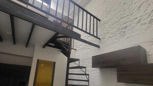 Una cocina compacta con encimera negra, una escalera de caracol y un pequeño comedor con dos sillas.